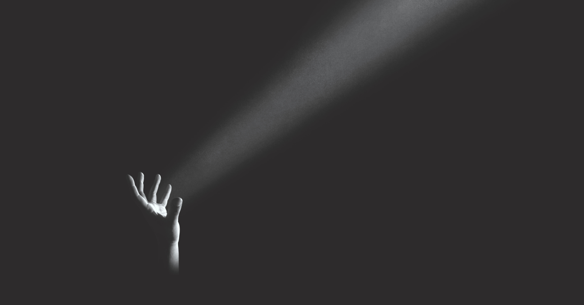 Mano en oscuridad que ilumina desde abajo