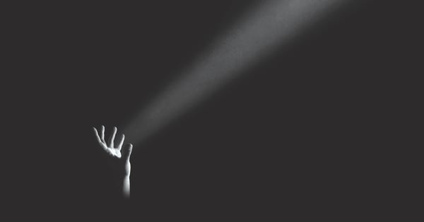 Mano en oscuridad que ilumina desde abajo