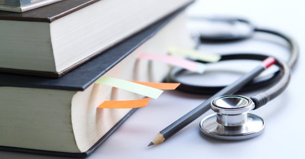 Libros de administración hospitalaria apilados junto a estetoscopio