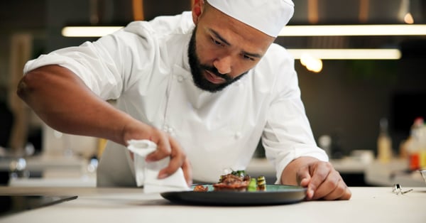 Chef prepara receta estandarizada en cocina de restaurante