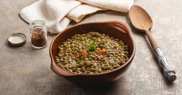 Plato rudimentario con lentejas y cuchara de madera