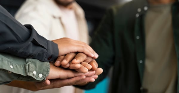 Hombres unen las manos en trabajo colaborativo