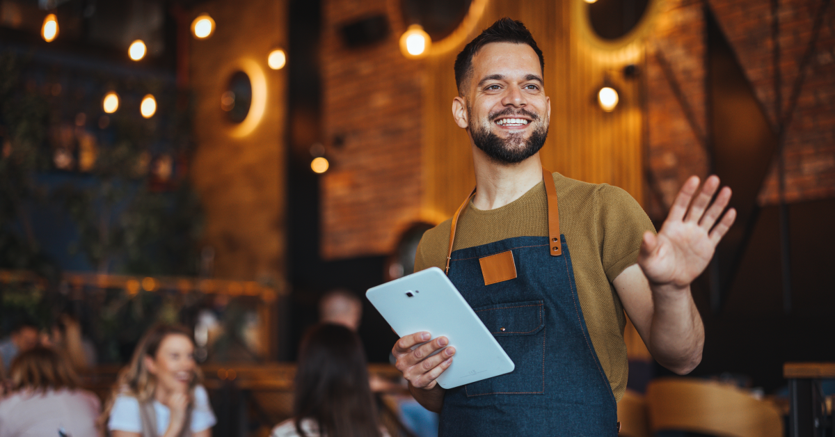 Mesero amable al frente de restaurante atendiendo clientes