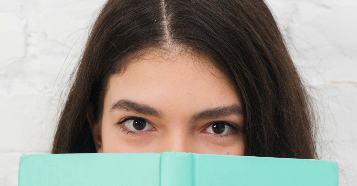 Estudiante de filosofía con cuaderno cubriendo rostro