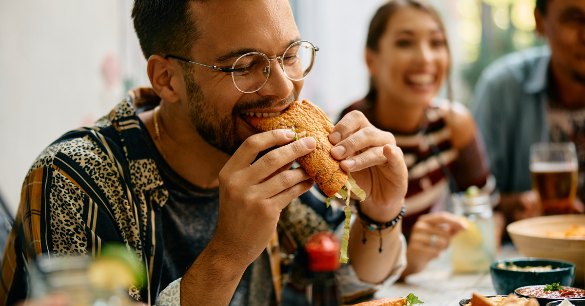 Hombre come con amigos en restaurante mexicano