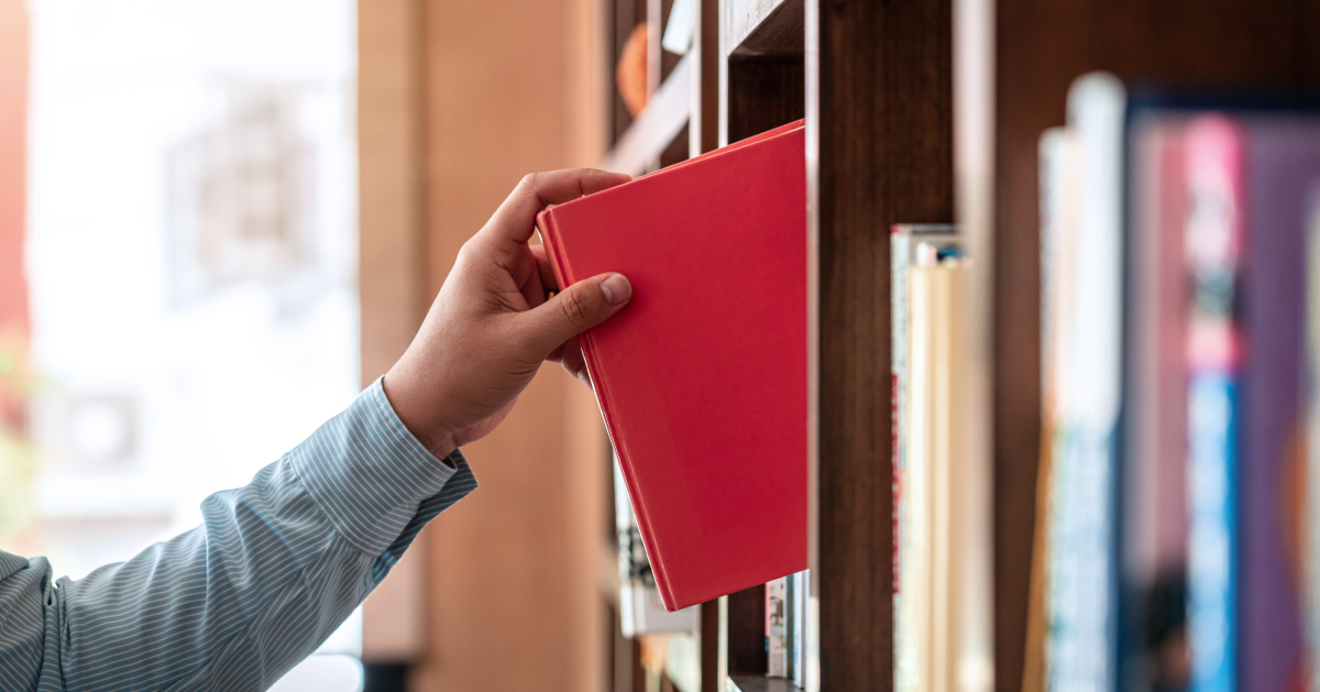 Hombre toma libro de estrategia empresarial de un librero