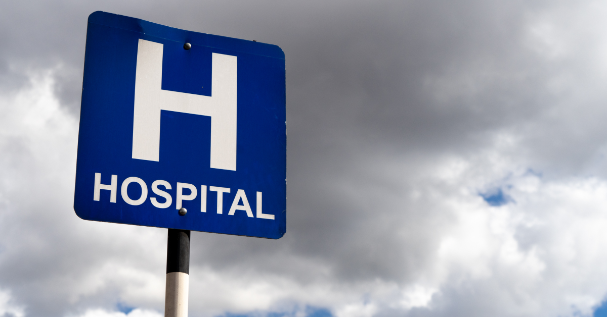 Letrero azul de hospital con fondo nublado