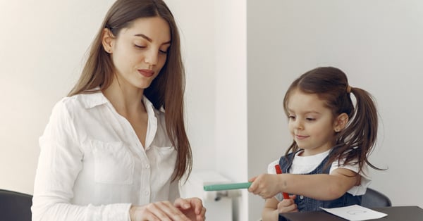 Pedagoga infantil ayuda a niña pequeña