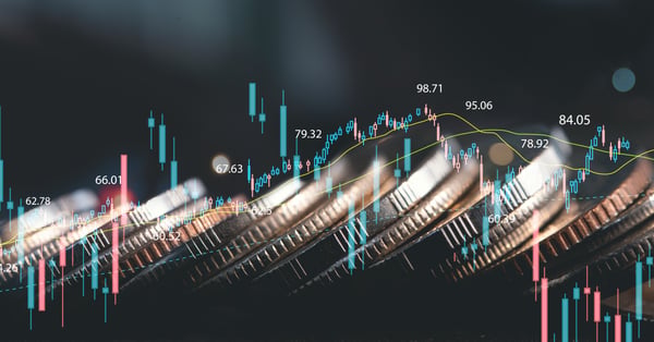 Monedas apiladas detrás de gráfico de velas