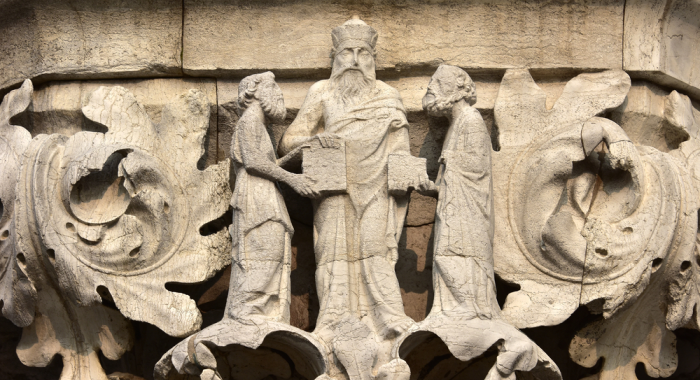 Escultura de Aristóteles enseñando a dos santos medievales