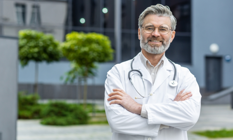 Director médico exitoso parado frente a hospital