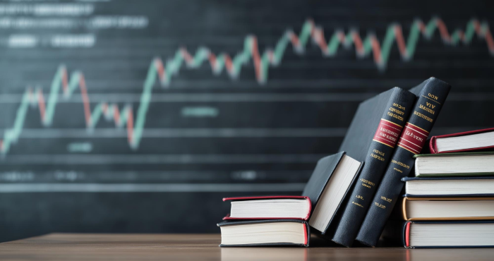 Libros de economía empresarial frente a pizarrón con gráfica