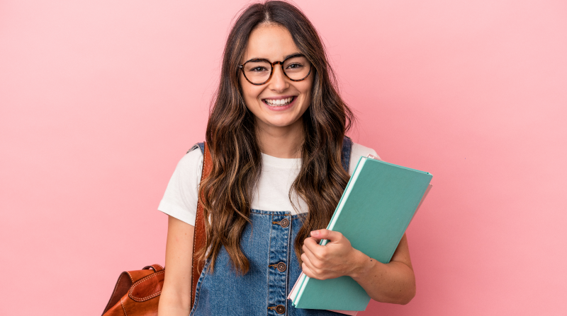 Adolescente de preparatoria con sonrisa y cuaderno en la mano