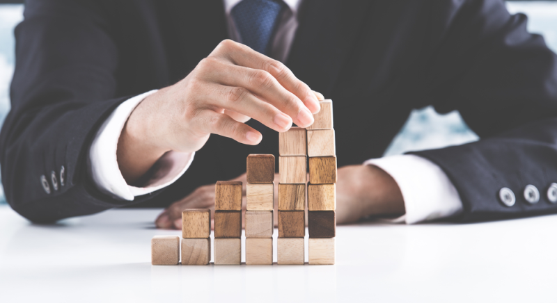 Empresario arma bloques de madera, representa estructuralismo administrativo