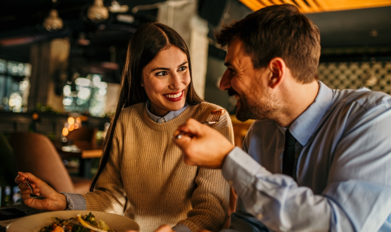 Una pareja alegre comiendo en restaurante elegante