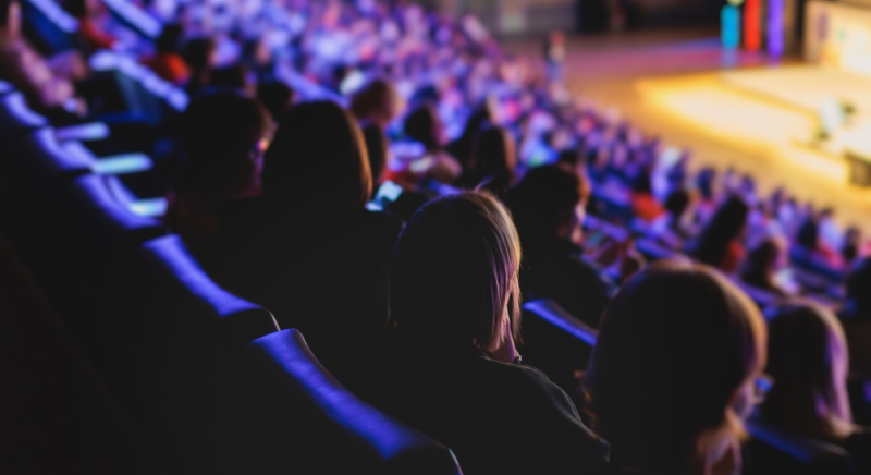 Público sentado espera comienzo de evento con presentador