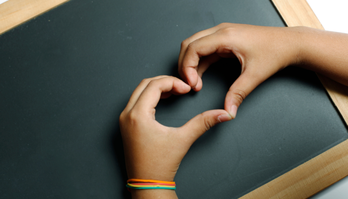 Alumna de primaria forma corazón con manos