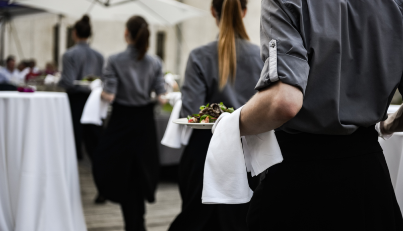 Meseros que conforman personal de restaurante sirven platos