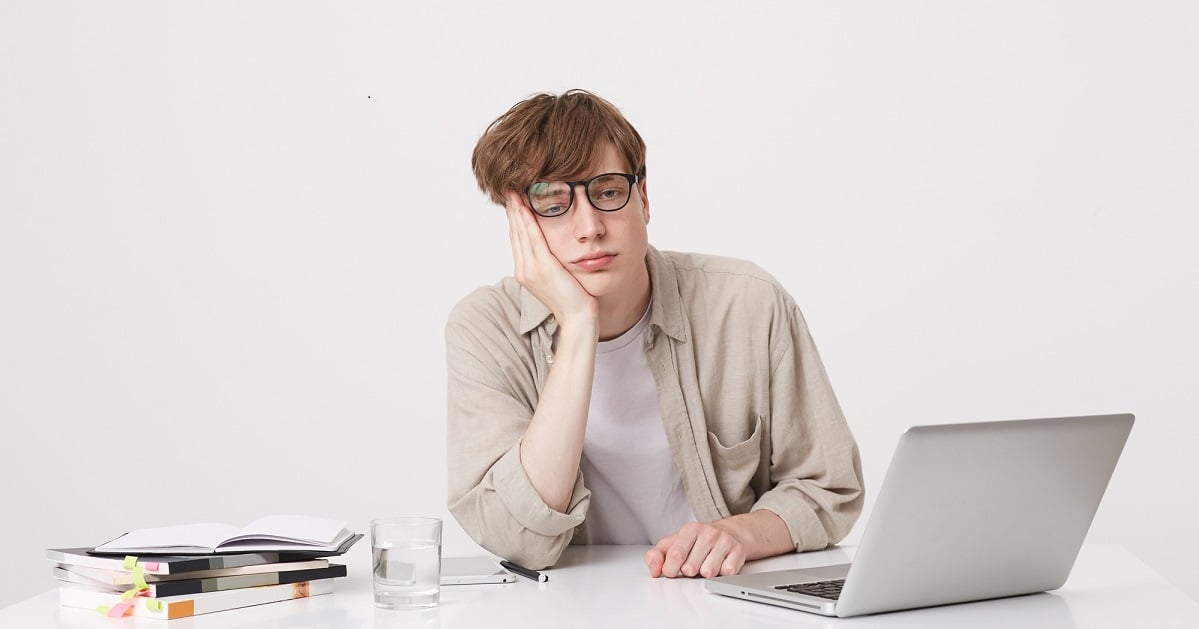 portrait-amazed-young-man-student-wears-beige-shirt-looks-surprised-study-table-with-laptop-computer-notebooks-isolated-white-wall