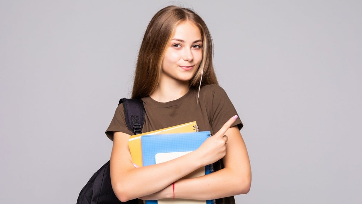 portrait-cute-young-brunette-student-holding-exercise-books-isolated-white-wall