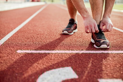 primer-plano-de-mujer-joven-atar-zapatos-deportivos-en-pista-roja