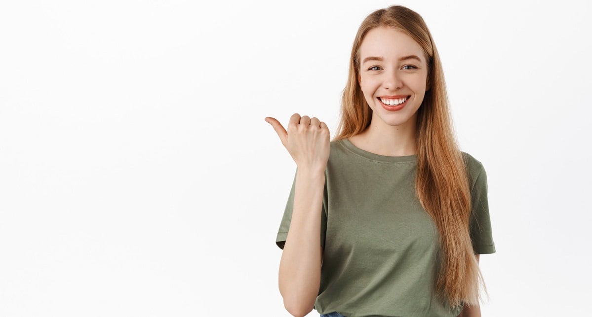 smiling-confident-girl-student-pointing-thumb-left-looking-determined-give-advice-recommend-this-product-showing-advertisement-copy-space-white-wall