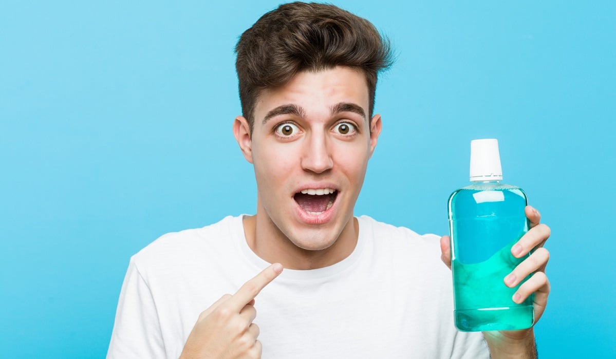 young-caucasian-man-holding-mouthwash-surprised-pointing-himself-smiling-broadly