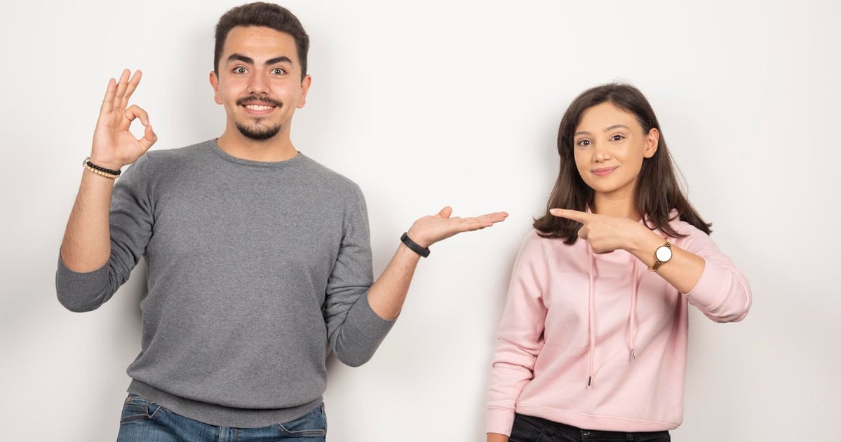 young-couple-pointing-themselves-white