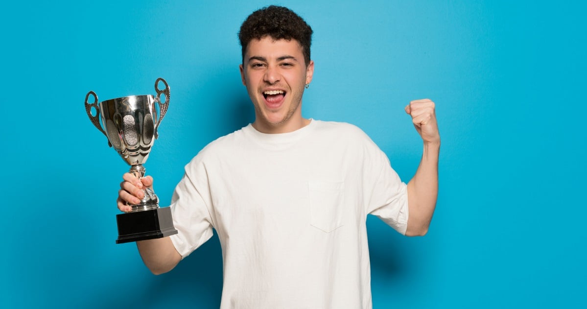 young-man-blue-background-holding-trophy