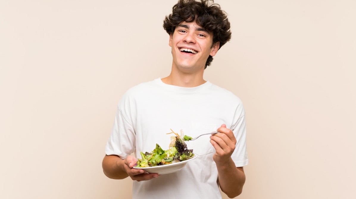 young-man-with-salad-isolated-green-wall